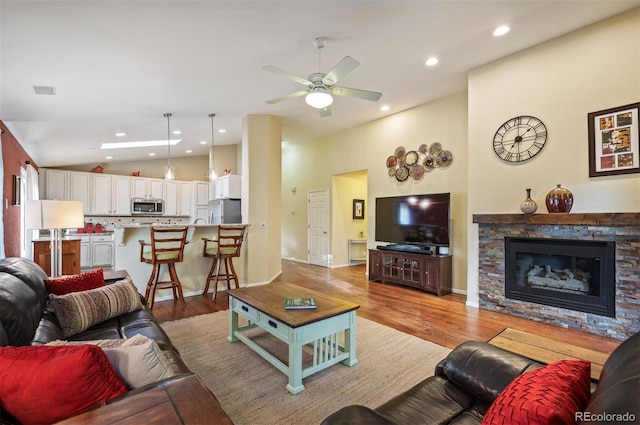 6480 Moss Cir, Arvada, CO 80007 - living area featuring light wood finished floors, ceiling fan, a stone fireplace, recessed lighting, and high vaulted ceiling