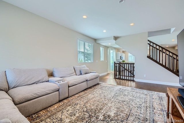 living room featuring stairs, baseboards, wood finished floors, and recessed lighting