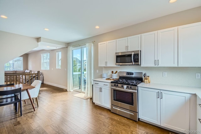 kitchen with tasteful backsplash, wood finished floors, stainless steel appliances, light countertops, and recessed lighting