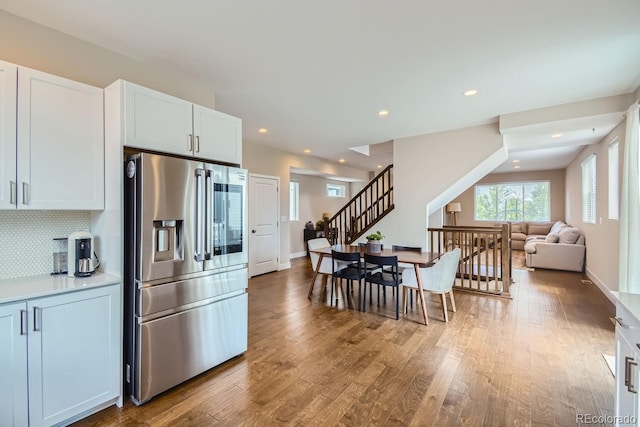 kitchen featuring decorative backsplash, wood finished floors, light countertops, stainless steel refrigerator with ice dispenser, and recessed lighting