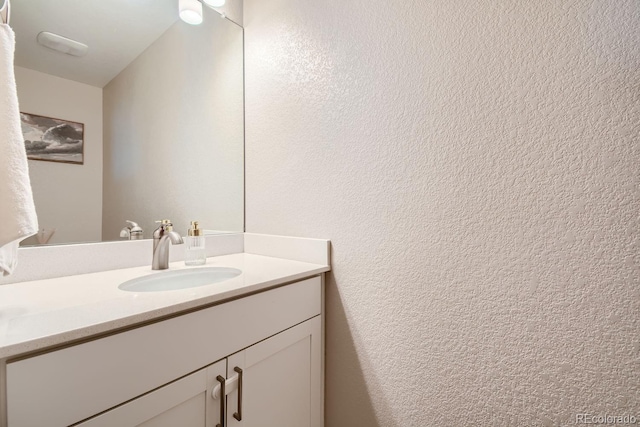 bathroom with a textured wall and vanity