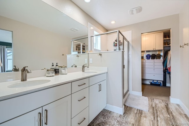 full bath featuring a walk in closet, a sink, a shower stall, and double vanity