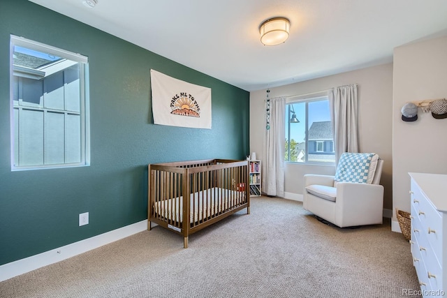 bedroom with a crib, baseboards, and carpet flooring