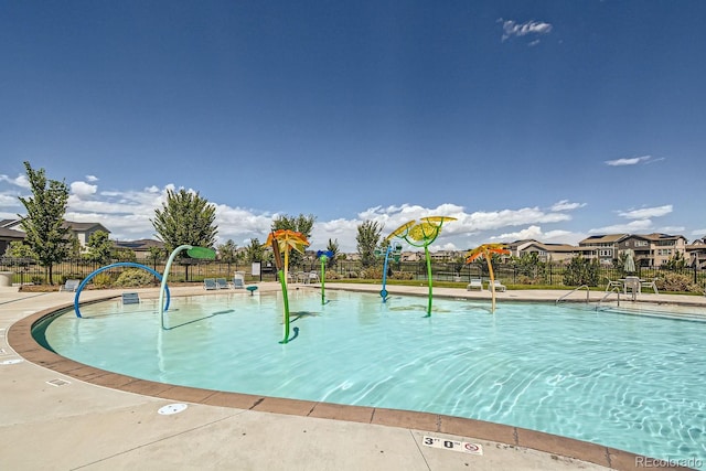 view of swimming pool featuring a water play area, a residential view, and fence