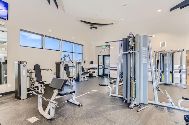 exercise room with a towering ceiling, visible vents, and recessed lighting