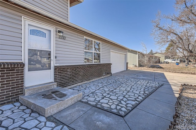 exterior space with a garage, brick siding, and driveway