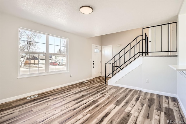 entryway with baseboards, stairs, visible vents, and wood finished floors