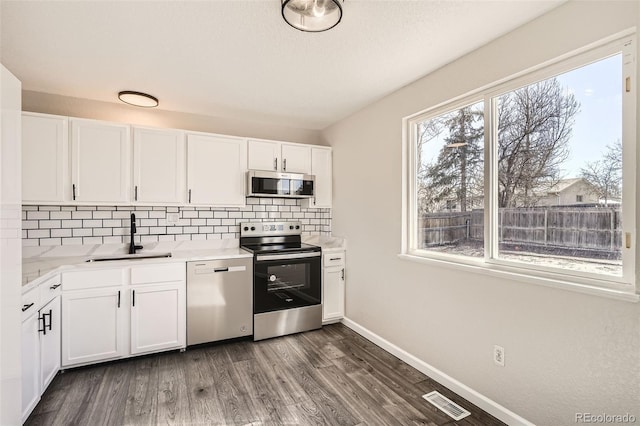 kitchen featuring light countertops, visible vents, decorative backsplash, appliances with stainless steel finishes, and a sink