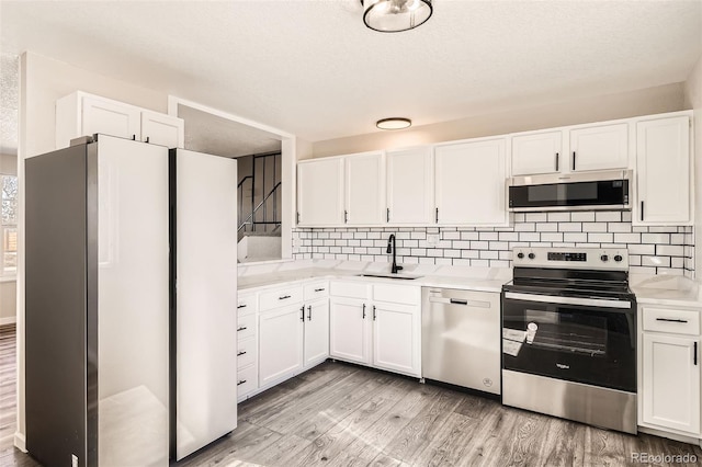 kitchen with light countertops, appliances with stainless steel finishes, light wood-type flooring, and a sink