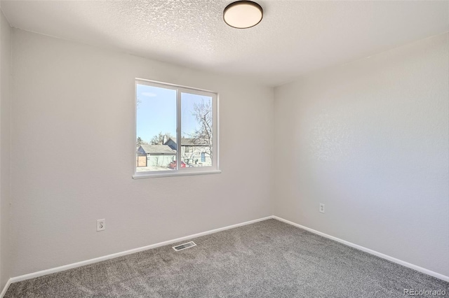 carpeted spare room with baseboards, visible vents, and a textured ceiling