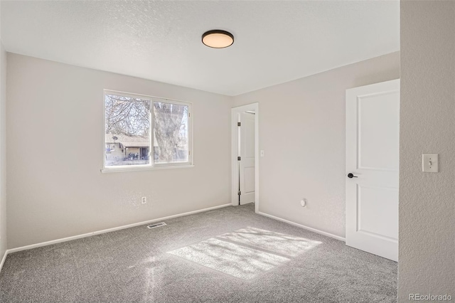 spare room with baseboards, carpet flooring, visible vents, and a textured ceiling