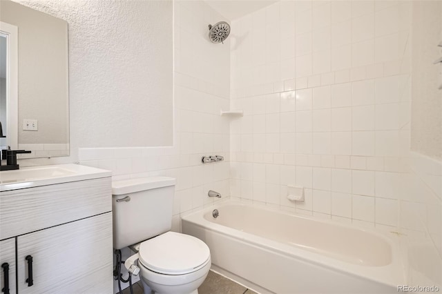 bathroom with toilet, a textured wall, washtub / shower combination, and vanity