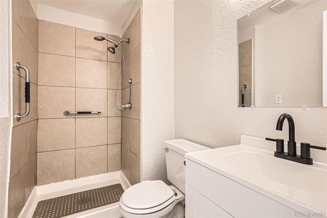 bathroom featuring toilet, a textured wall, a shower stall, and vanity