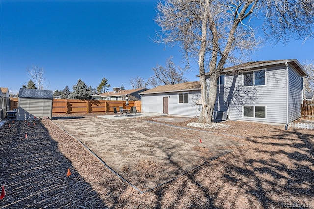 back of house featuring a storage unit, a patio area, a fenced backyard, and an outdoor structure