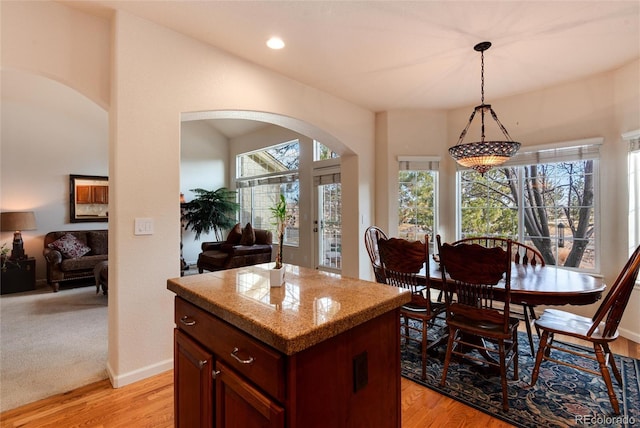 kitchen with light hardwood / wood-style flooring, a kitchen island, and hanging light fixtures