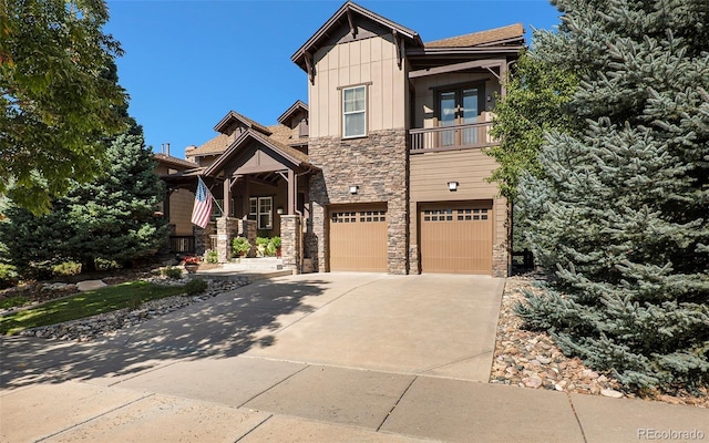 craftsman inspired home with an attached garage, a balcony, stone siding, driveway, and board and batten siding