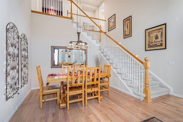 dining room with stairs, wood finished floors, a towering ceiling, and baseboards