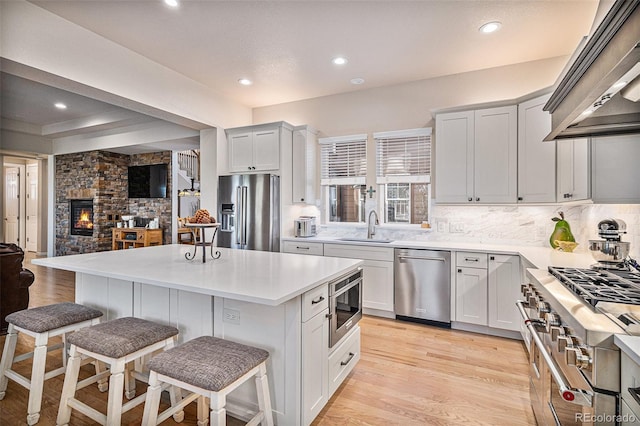 kitchen featuring premium range hood, a breakfast bar, a sink, high quality appliances, and light wood-type flooring