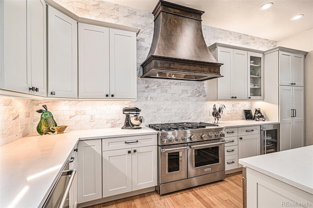 kitchen featuring light wood finished floors, double oven range, custom exhaust hood, and light countertops