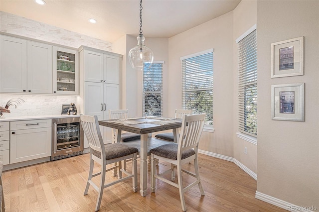 dining area with light wood-type flooring, beverage cooler, baseboards, and recessed lighting