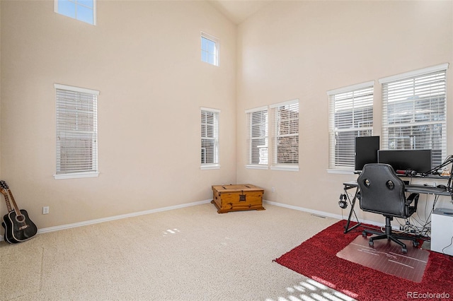 office space featuring carpet floors, a high ceiling, baseboards, and a wealth of natural light