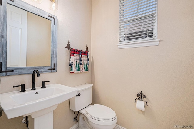 bathroom with a sink, toilet, and baseboards