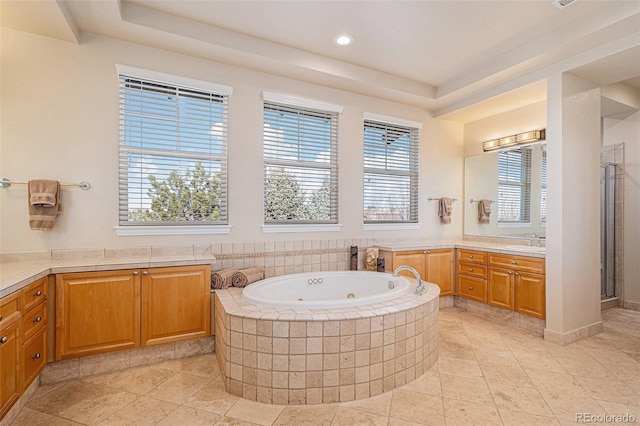 bathroom with a stall shower, a tray ceiling, vanity, and a tub with jets