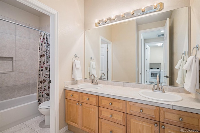 bathroom featuring double vanity, a sink, toilet, and tile patterned floors