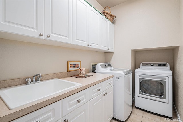 washroom featuring cabinet space, washing machine and dryer, light tile patterned floors, and a sink