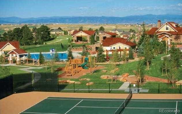 view of tennis court with a residential view, fence, a mountain view, and playground community