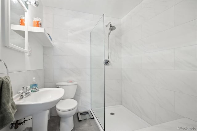 bathroom featuring tiled shower, sink, tile walls, and toilet