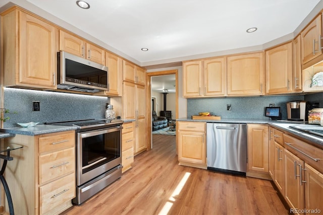 kitchen with tasteful backsplash, light brown cabinets, light hardwood / wood-style floors, and appliances with stainless steel finishes