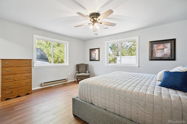 bedroom with ceiling fan, multiple windows, a baseboard radiator, and light hardwood / wood-style flooring