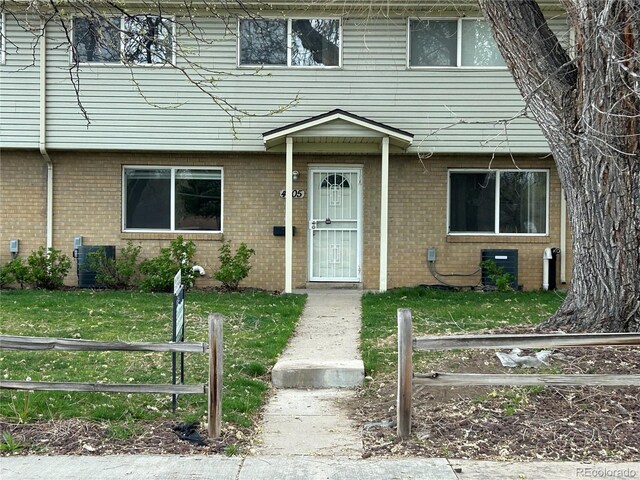 view of property featuring brick siding, fence, and a front yard