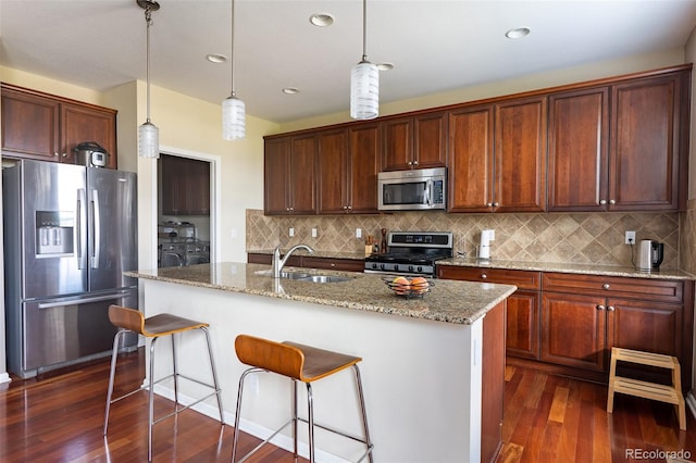 kitchen with an island with sink, backsplash, sink, appliances with stainless steel finishes, and dark hardwood / wood-style flooring