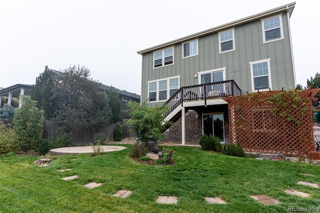 back of property with a yard, a deck, and a patio