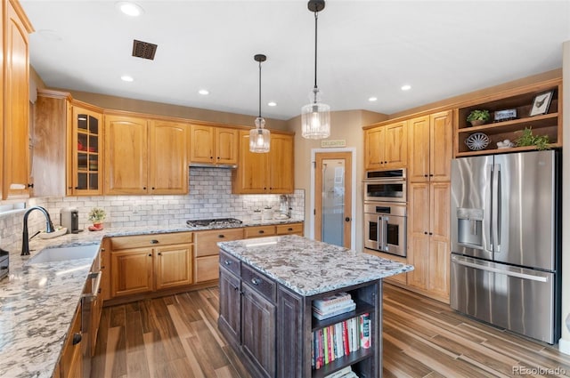 kitchen featuring sink, stainless steel appliances, light stone countertops, a kitchen island, and decorative backsplash