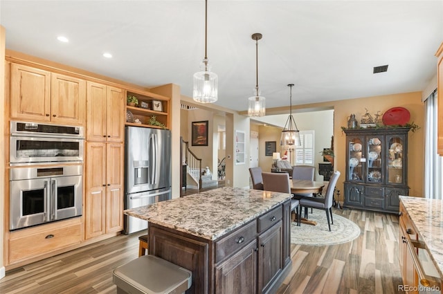 kitchen featuring dark wood-type flooring, dark brown cabinetry, hanging light fixtures, stainless steel appliances, and light stone countertops