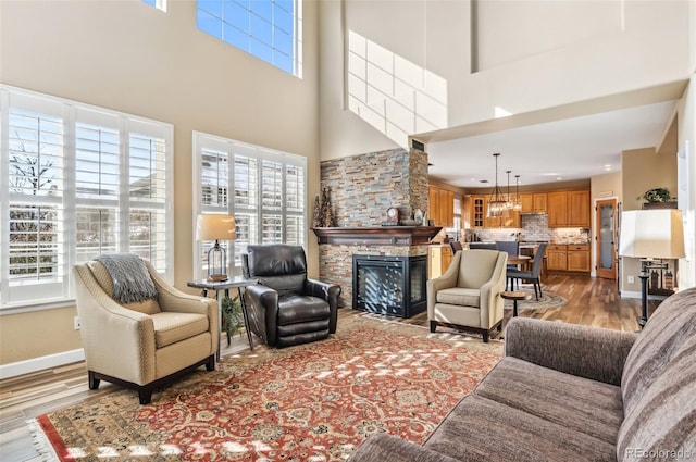 living room featuring a towering ceiling, a fireplace, and light hardwood / wood-style flooring