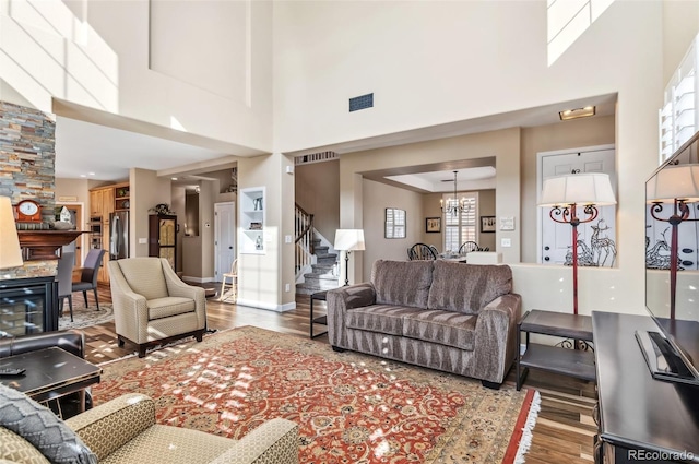 living room with hardwood / wood-style flooring, a towering ceiling, and a chandelier