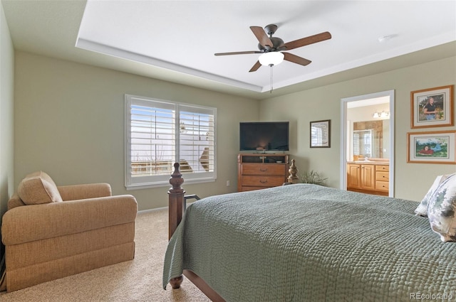 bedroom featuring a raised ceiling, ensuite bathroom, carpet flooring, and ceiling fan