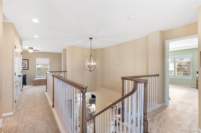 hall featuring light carpet and a chandelier