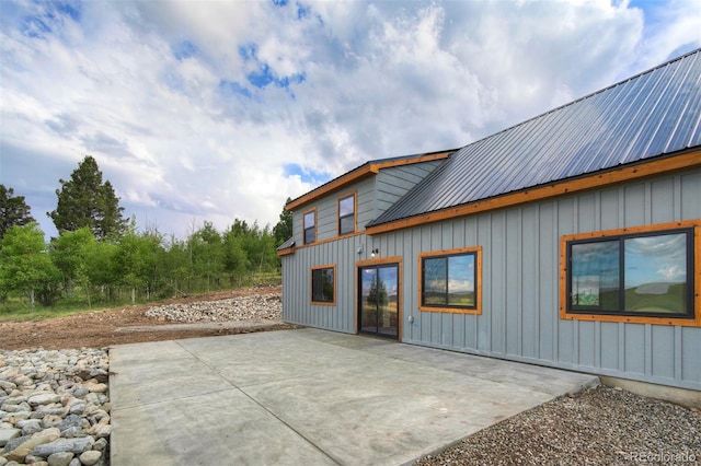 rear view of house featuring metal roof, a patio, and board and batten siding