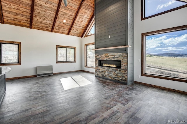 unfurnished living room with high vaulted ceiling, a stone fireplace, wooden ceiling, wood finished floors, and baseboards