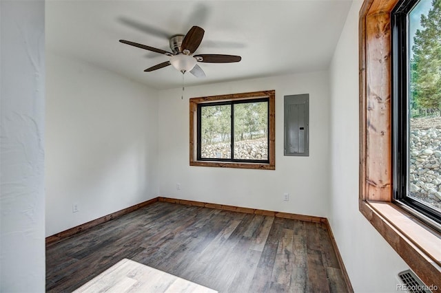 empty room featuring ceiling fan, wood finished floors, visible vents, baseboards, and electric panel