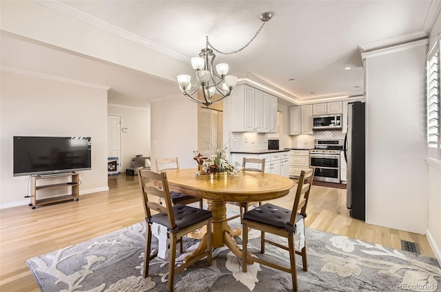 dining area with an inviting chandelier, ornamental molding, and light hardwood / wood-style flooring