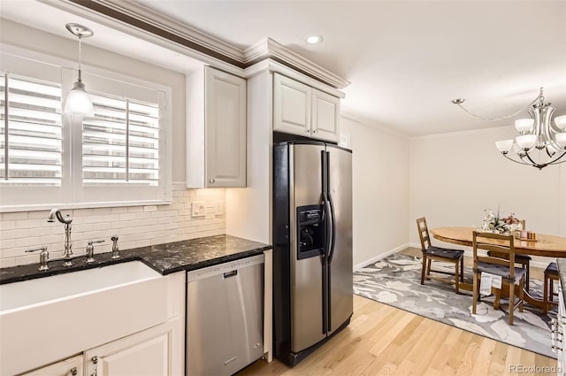 kitchen featuring appliances with stainless steel finishes, decorative light fixtures, white cabinetry, ornamental molding, and light hardwood / wood-style flooring