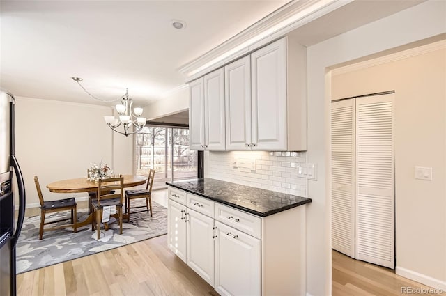 kitchen with tasteful backsplash, white cabinetry, pendant lighting, and light hardwood / wood-style floors