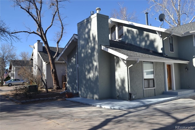 9551 E Chenango Ave, Greenwood Village, CO 80111 - exterior space featuring stucco siding, roof with shingles, and a chimney