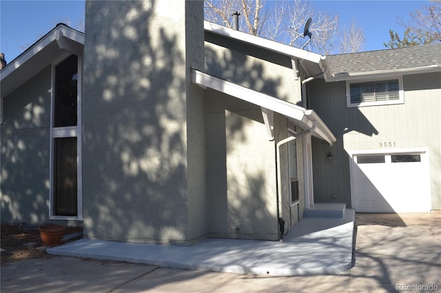 9551 E Chenango Ave, Greenwood Village, CO 80111 - rear view of property featuring stucco siding, a shingled roof, and a garage